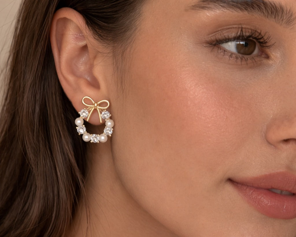 Close-up of a woman wearing a gold bow earring with pearls.