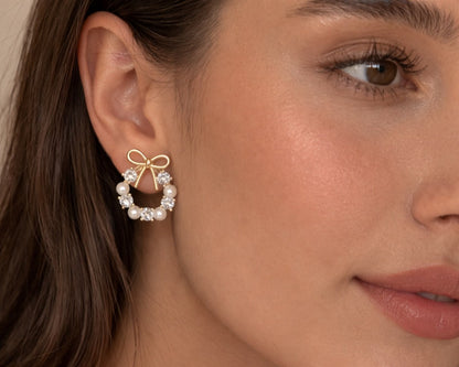 Close-up of a woman wearing a gold bow earring with pearls.