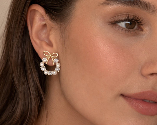 Close-up of a woman wearing a gold bow earring with pearls.
