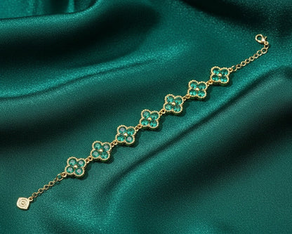Gold bracelet with green gemstones on a green satin background