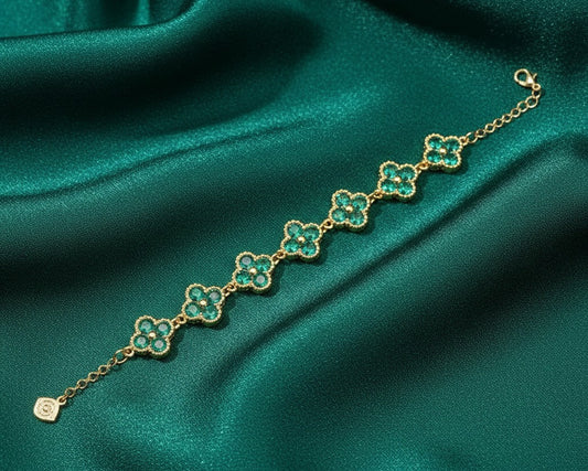 Gold bracelet with green gemstones on a green satin background