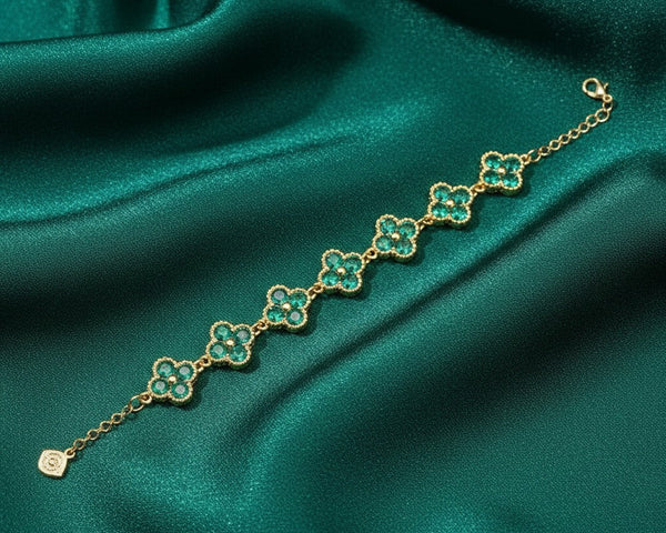 Gold bracelet with green gemstones on a green satin background