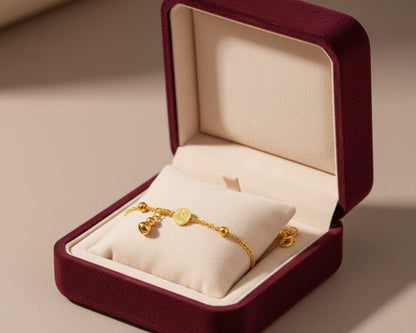 Gold bracelet in a burgundy jewelry box on a beige surface