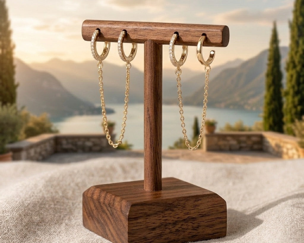 Wooden jewelry stand with gold chain earrings against a scenic background