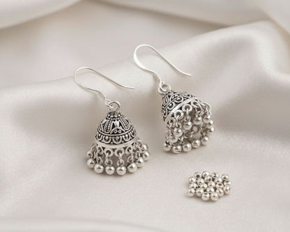 Silver earrings with pearl-like beads on a white fabric background