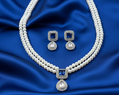 Pearl necklace with blue gemstones and matching earrings on a blue satin background