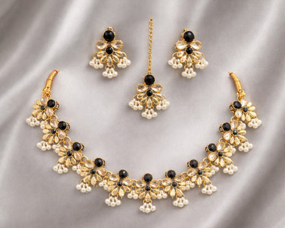 Gold necklace with black stones and matching earrings on a gray fabric background