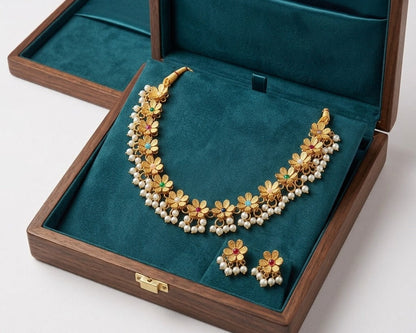 Gold necklace with floral design and pearl accents in a jewelry box