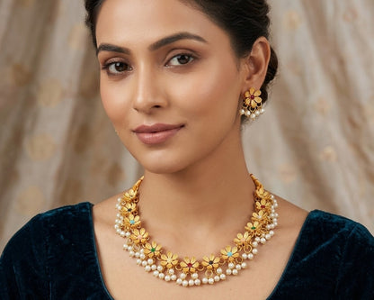 Woman wearing a gold necklace and earrings with a beige curtain background