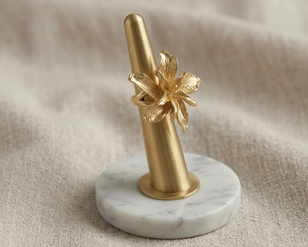Decorative object with gold floral design on a marble base against a beige fabric background
