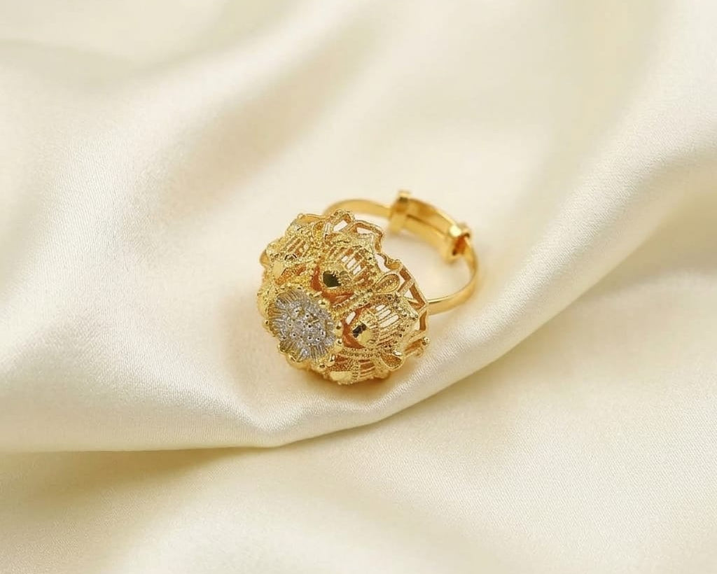 Gold ring with intricate design on a beige satin background