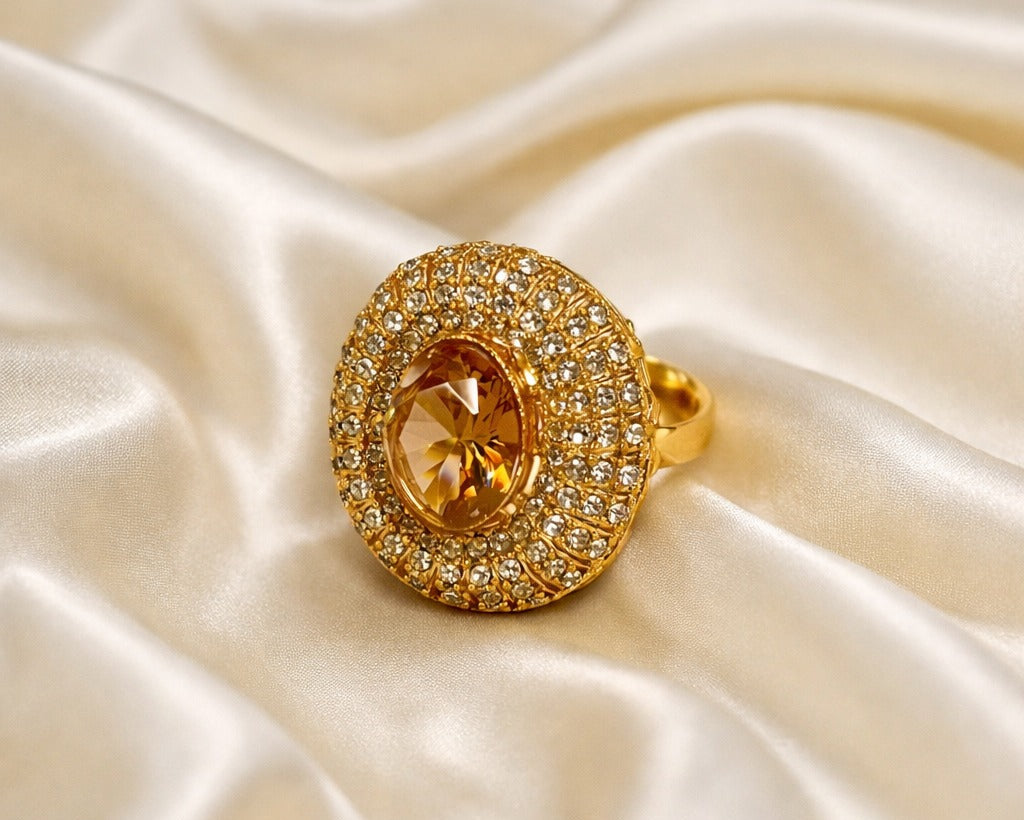 Gold ring with a central gemstone on a satin surface