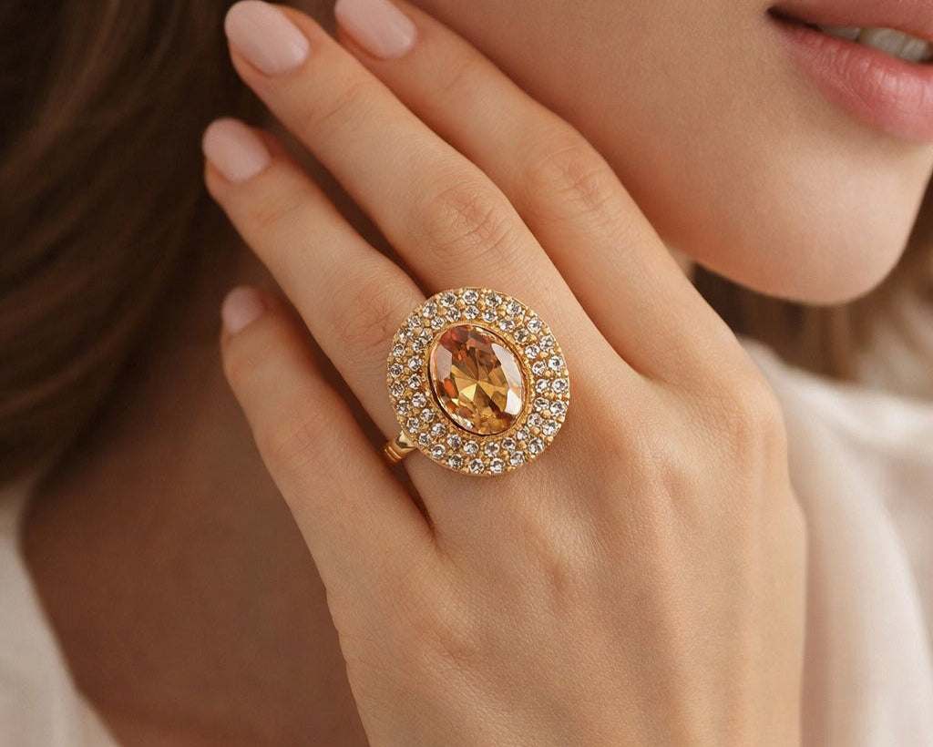 Close-up of a hand wearing a gold ring with a large gemstone.