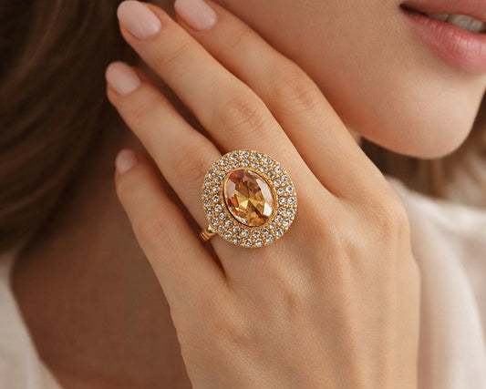 Close-up of a hand wearing a gold ring with a large gemstone.
