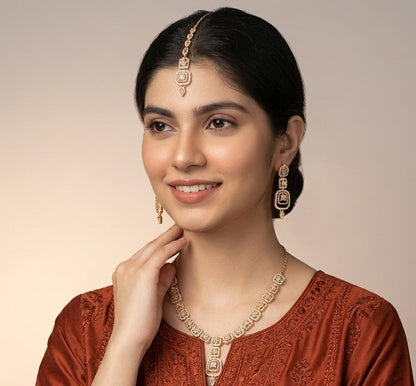 Woman wearing a rust-colored traditional outfit with jewelry against a beige background