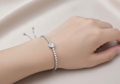 Silver bracelet with a clear gemstone on a wrist against a neutral background