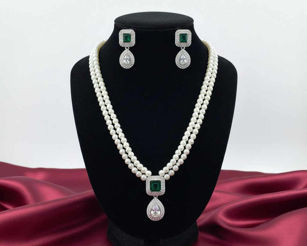 Pearl necklace and earrings set on a black stand with a red fabric background