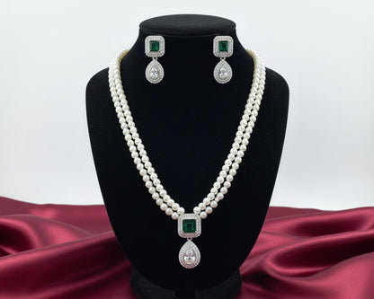 Pearl necklace and earrings set on a black stand with a red fabric background
