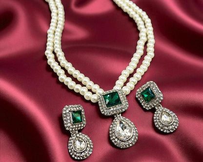 Pearl necklace with emerald and diamond earrings on a red satin background