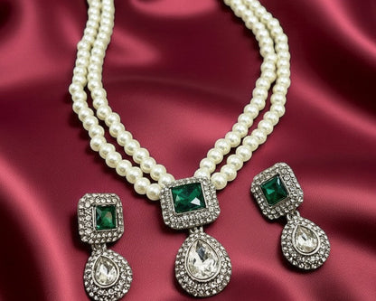 Pearl necklace with green gemstone pendants on a red satin background