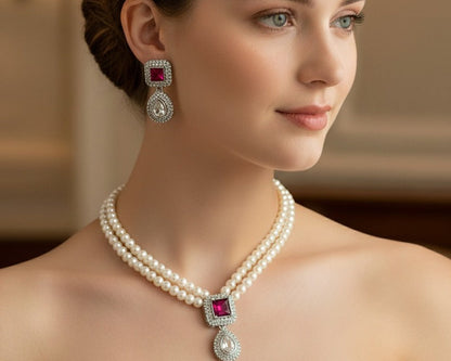 Woman wearing a pearl necklace and earrings with red gemstones in an elegant setting.