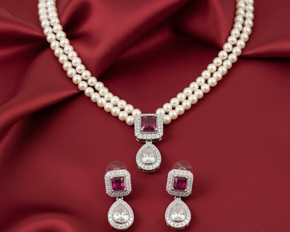 Pearl necklace with red gemstones and matching earrings on a red fabric background